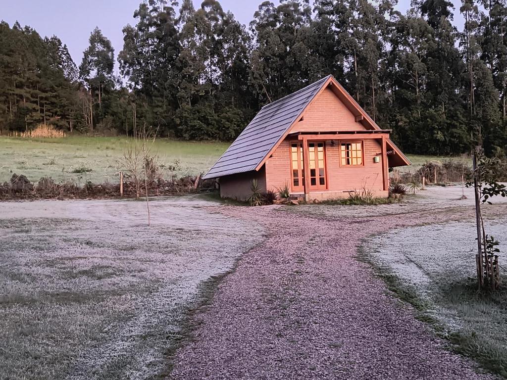 a small house in a field next to a dirt road at Refúgio Verde - Cabana Quero-Quero in Nova Petrópolis