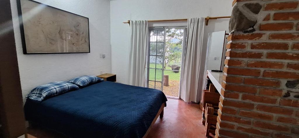 een slaapkamer met een bed en een bakstenen muur bij Posada Meztitla in Tepoztlán