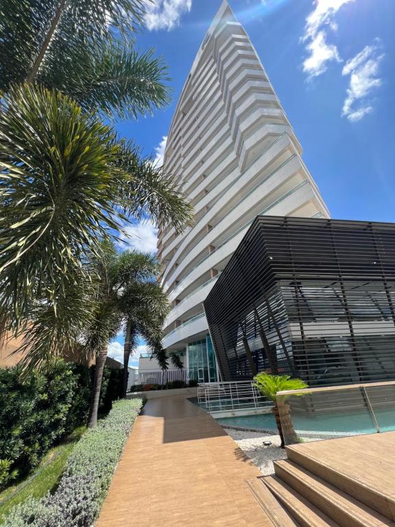 Un edificio alto con una palmera delante. en Apartamento confortável, localização extra -recepção 24h- Varanda com vista panorâmica, en Juazeiro do Norte