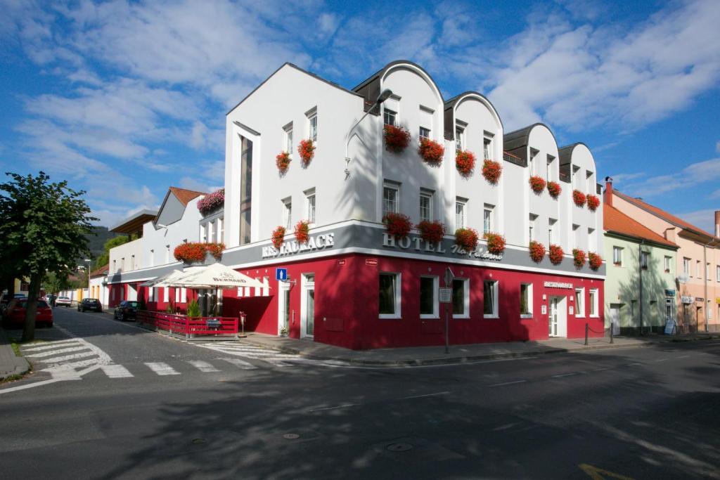 a red and white building with flower boxes on it at Hotel Na Pekárně in Sušice