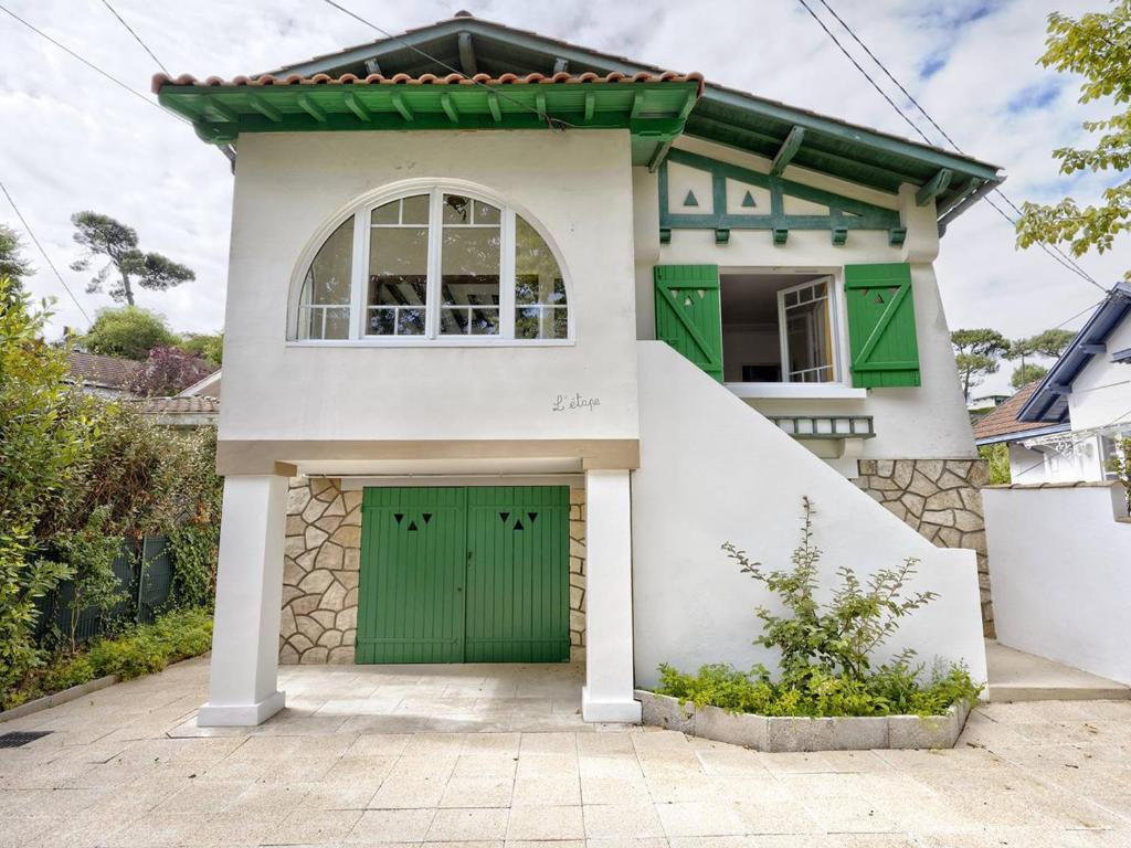 une maison blanche avec une porte de garage verte dans l'établissement Arcachon : Appartement T4 avec terrasse et parking à 400m de la plage ! - FR-1-433-128, à Arcachon