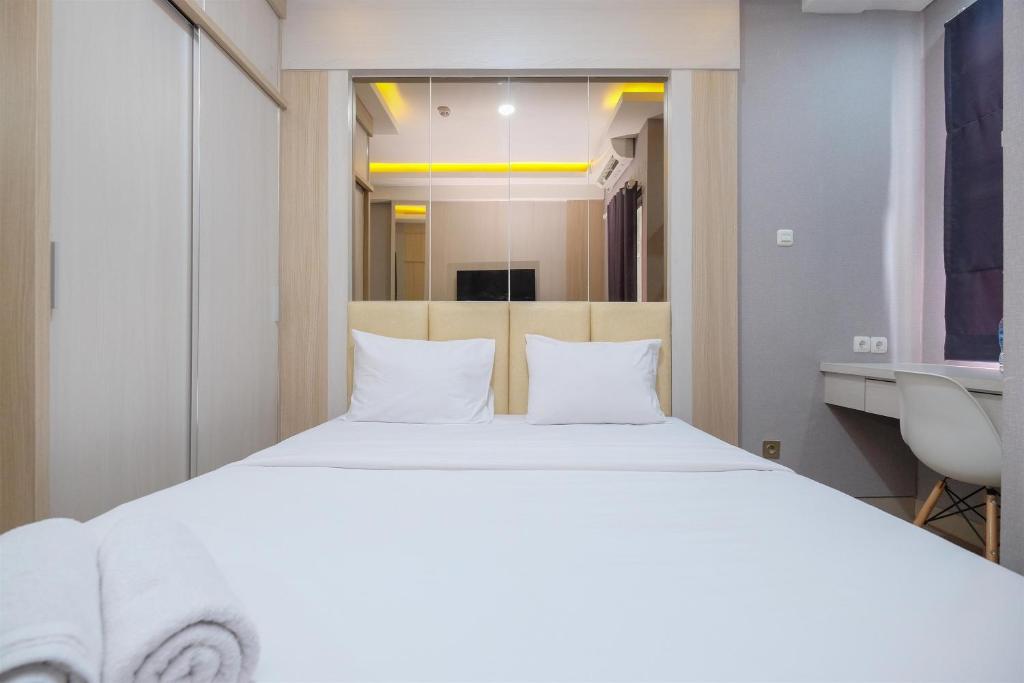 a bedroom with a large white bed and a sink at Cozy and Nice Studio at Transpark Cibubur Apartment By Travelio in Depok