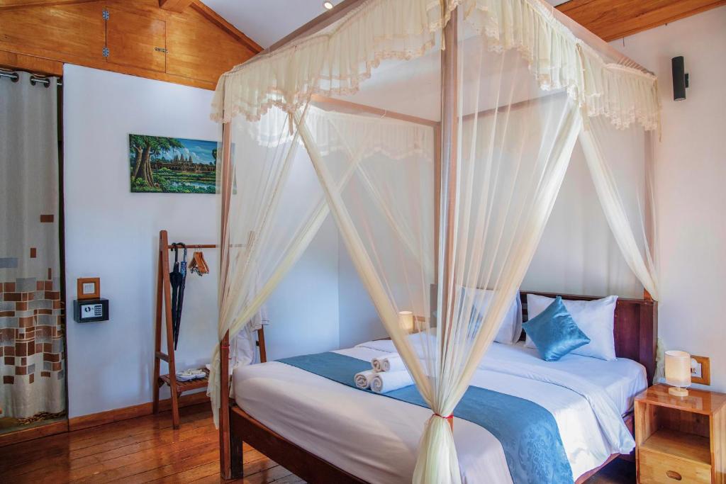 a bedroom with a canopy bed with white curtains at Habana Angkor Boutique Hotel in Siem Reap