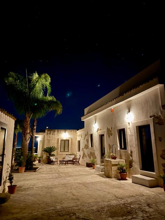 a house with a patio at night with a palm tree at Villa La Rosa in Chiaramonte Gulfi