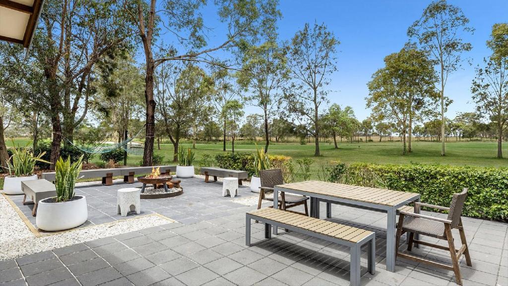 eine Terrasse mit Bänken und Tischen in einem Park in der Unterkunft Hunter Grange - The Vintage in Pokolbin