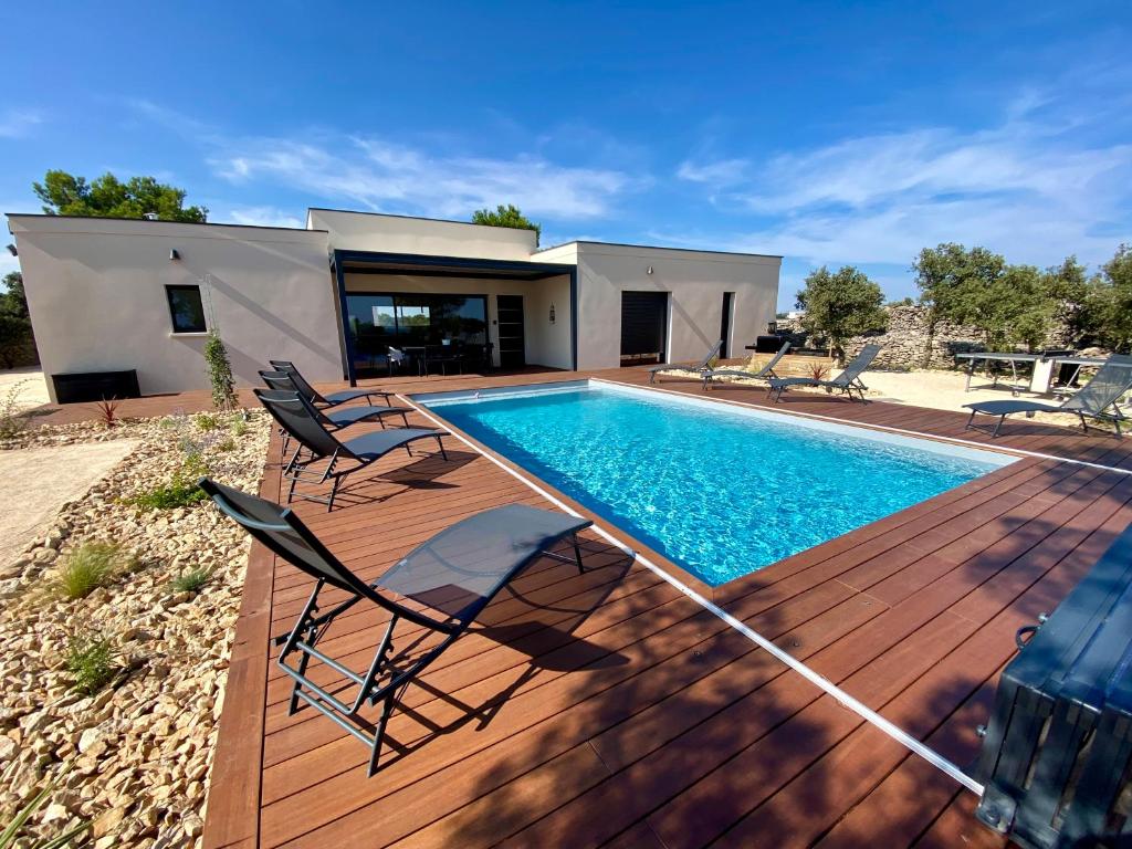 une terrasse avec une piscine et des chaises à côté d'une maison dans l'établissement Villa moderne piscine privative hauteurs de Nimes, à Nîmes