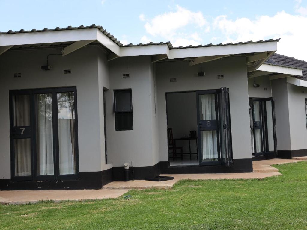 a house with glass doors and a green lawn at Tambarara Manor & Conference Centre in Harare