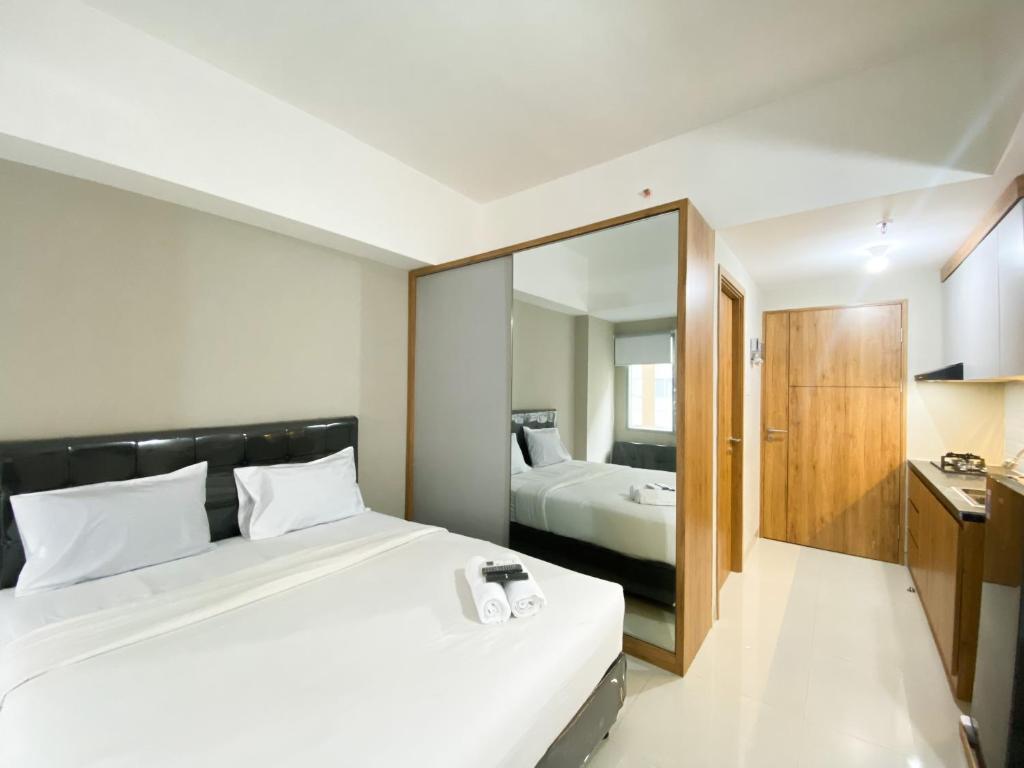 ブカシにあるMinimalist Studio Room Gateway Park LRT City Jatibening Apartment By Travelioの大きな白いベッドと鏡のある寝室
