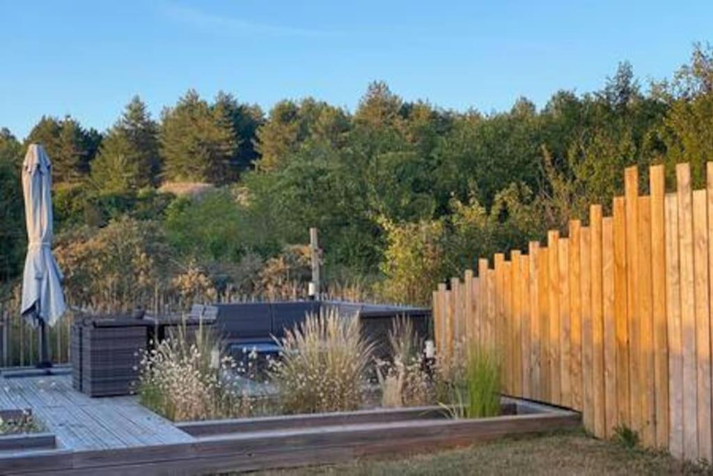 a backyard with a wooden fence and an umbrella at Entre dunes et pins in Merlimont