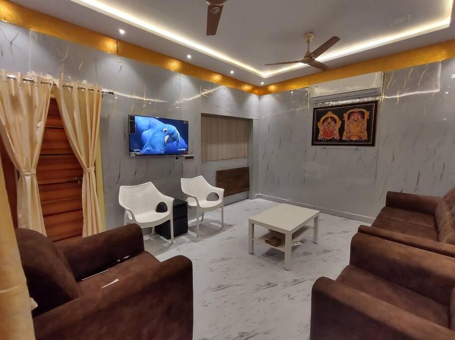 a living room with couches and a tv on a wall at Brindavanam Guest house in Elūru