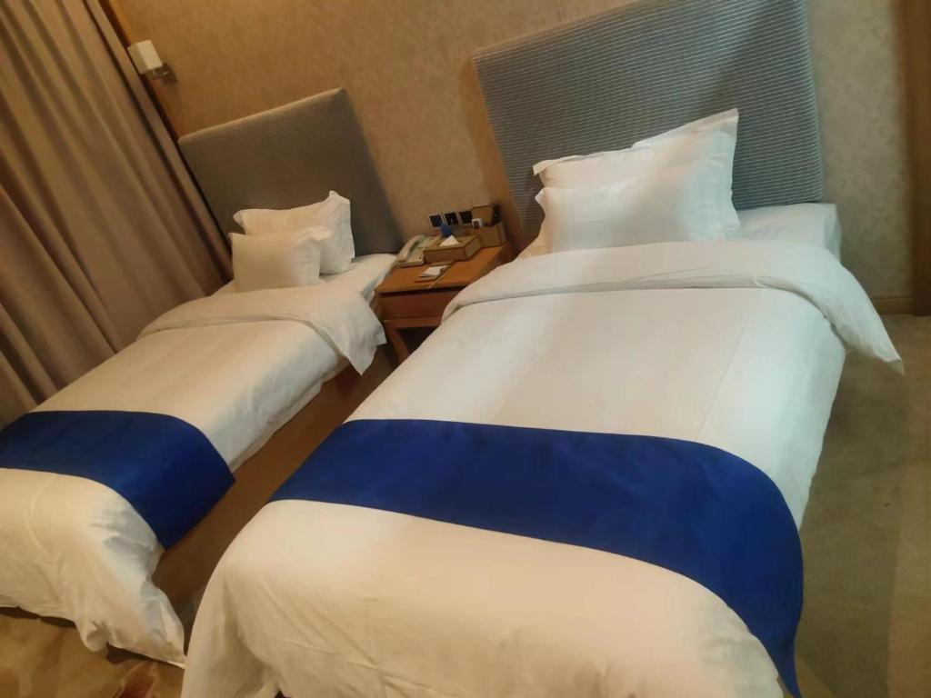 two beds in a hotel room with a phone at 海岸秀月楼酒店 in Shenzhen