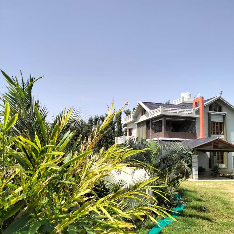 a house with palm trees in front of it at The Grassland homestay in Chikmagalūr