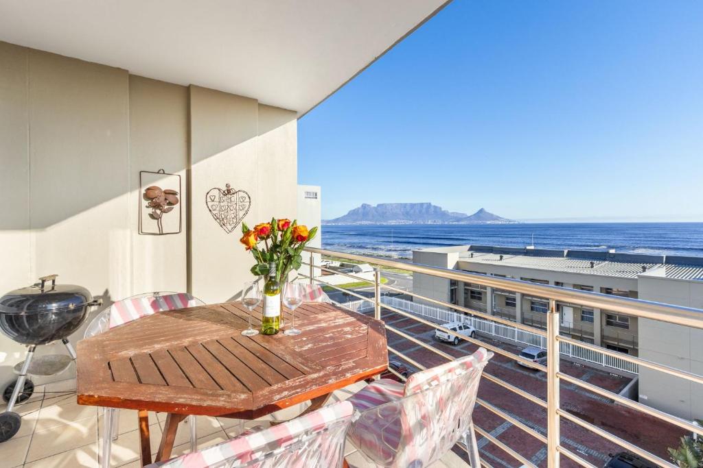 a balcony with a table and a view of the ocean at The Waves 302 in Bloubergstrand