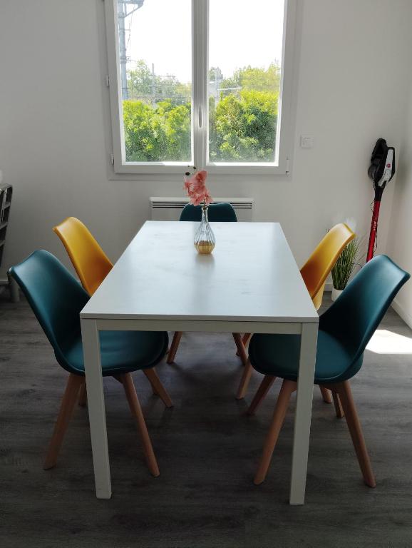 une table et des chaises blanches avec un vase au-dessus dans l'établissement Appartement Studio tout équipé refait à neuf, à Rambouillet