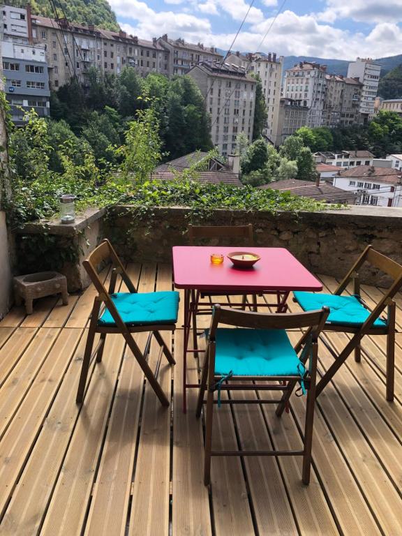 une table rose et deux chaises sur une terrasse dans l'établissement T2 avec terrasse calme et ensoleillée, à Saint-Claude
