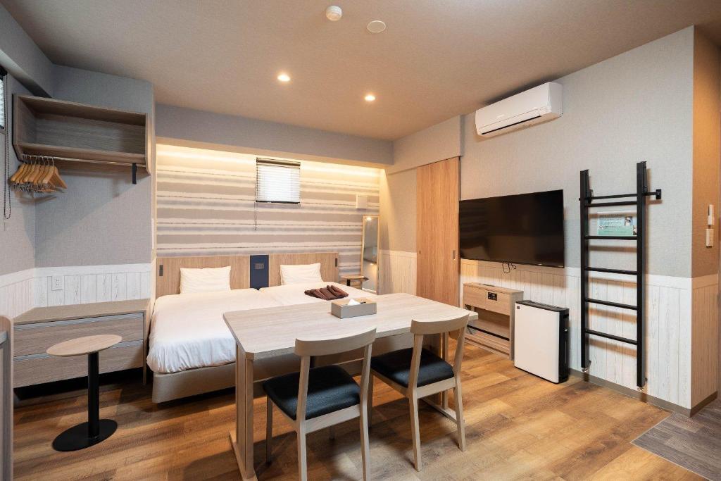 a bedroom with a bed and a table and a bed and a television at stayme THE HOTEL Ueno Ekimae in Tokyo