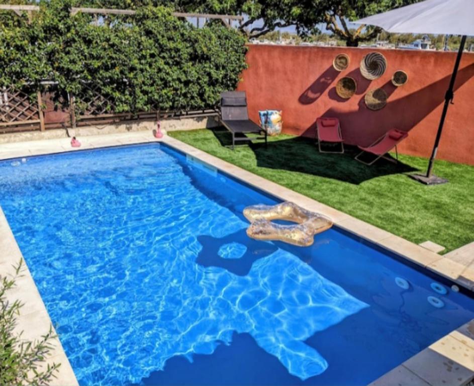 a swimming pool with blue water in a yard at La Cabane des Mouts- Piscine -Clim in Fleury