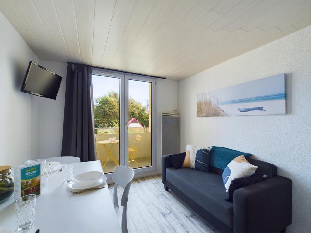 a living room with a couch and a table at À 150m de la plage, appartement mezzanine pour 4 in Les Bussolleries