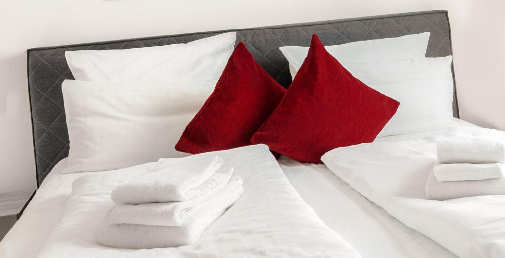 a bed with red pillows and white sheets at Zur Windmühle Restaurant - Hotel in Beckum
