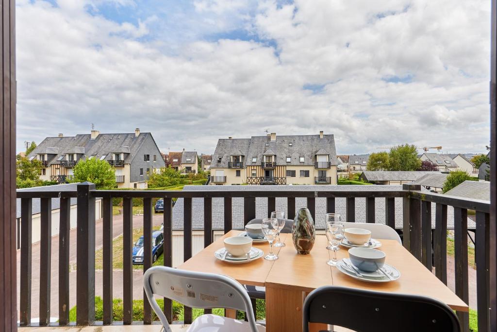 - une table sur un balcon avec vue sur les maisons dans l'établissement Le Repos de Cabourg - Appt à 650m de la plage, à Cabourg