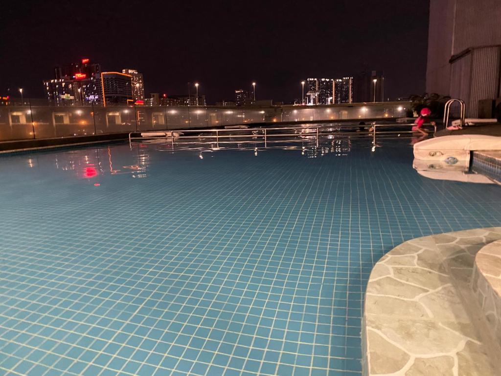 a swimming pool with a city skyline at night at WakakaPackers in Kuala Lumpur