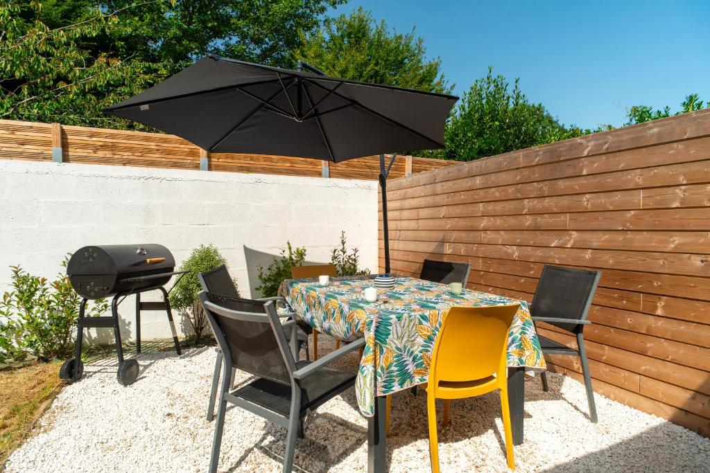 a table and chairs with an umbrella and a grill at L'Écrin d'Hennebont - Maison en pierre pour 8 in Hennebont