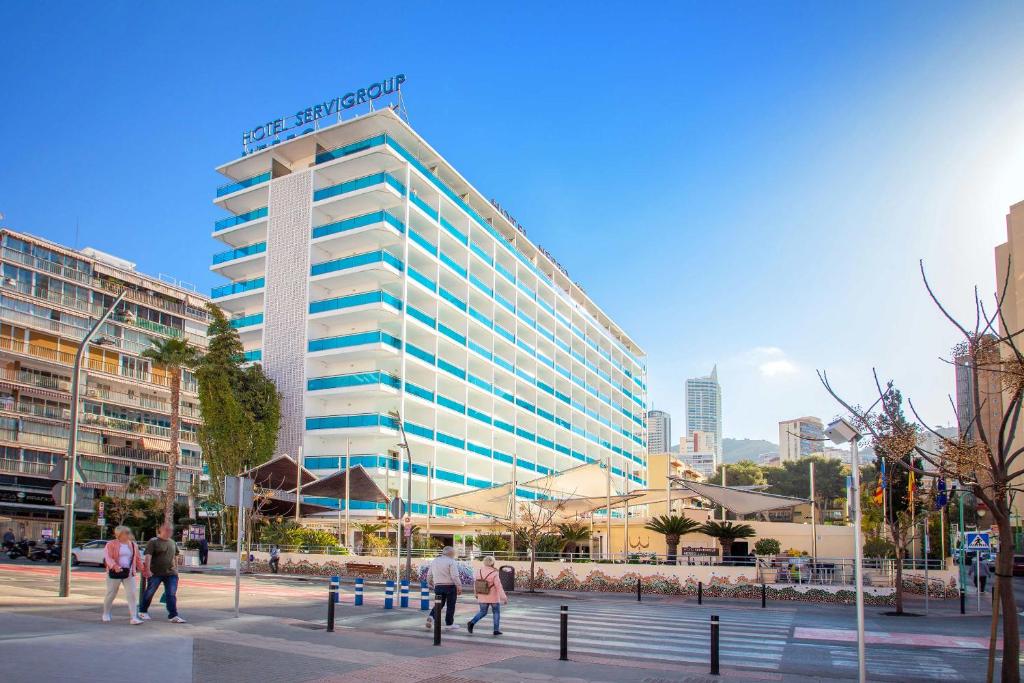 wysoki budynek z ludźmi przed nim. w obiekcie Hotel Servigroup Nereo w mieście Benidorm