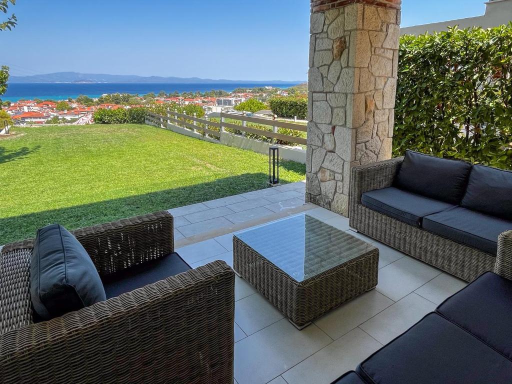 un patio con sillas de mimbre y una mesa de cristal en Villa Horizon Vista, en Chaniotis