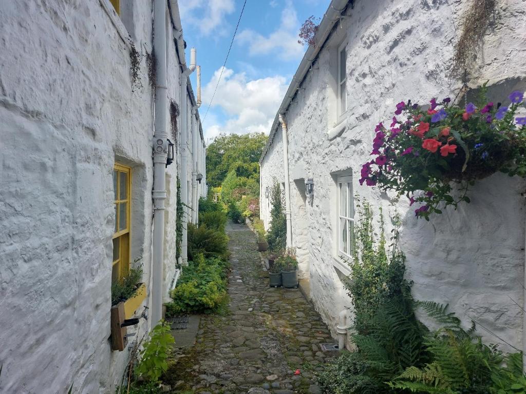 an alley between two white buildings with flowers at Blue Door - Kirkcudbright in Kirkcudbright
