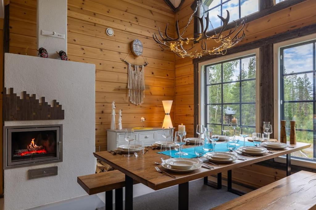 a dining room with a table and a fireplace at Kurjenkenkä by HiYlläs in Kittilä