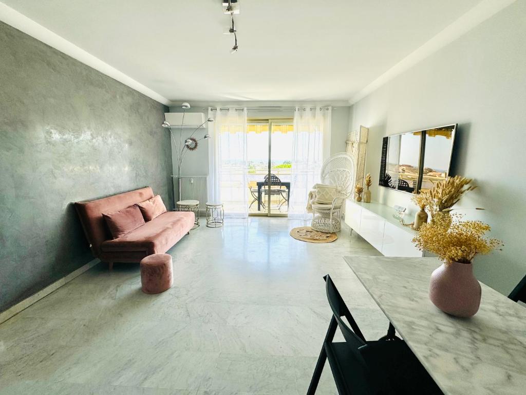 un salon avec un canapé rose et une table dans l'établissement Escapade Méditerranéenne, à Cagnes-sur-Mer