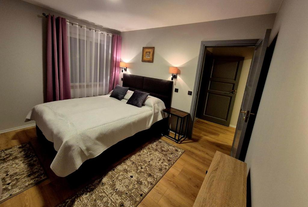 a bedroom with a large bed and a door at Butas Ežero 30 in Plateliai