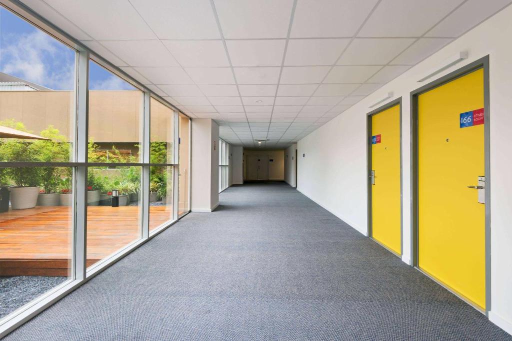 an empty corridor of a building with yellow doors at TRYP BY WYNDHAM São Paulo Airport - Hotel de Transito Terminal 3 -Lado Ar - Área restrita á passageiros já embarcados - Piso 1 in Guarulhos