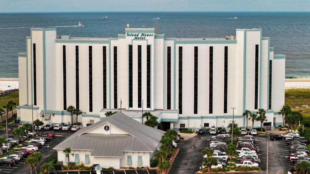 奥兰治比奇The Island House Hotel a Doubletree by Hilton的一座白色的大建筑,汽车停在停车场