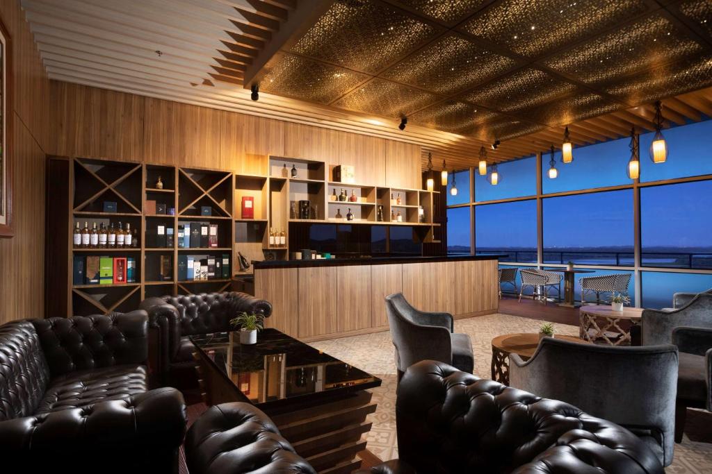 a room with leather couches and a bar with a view at Wyndham Panbil Batam in Batam Center