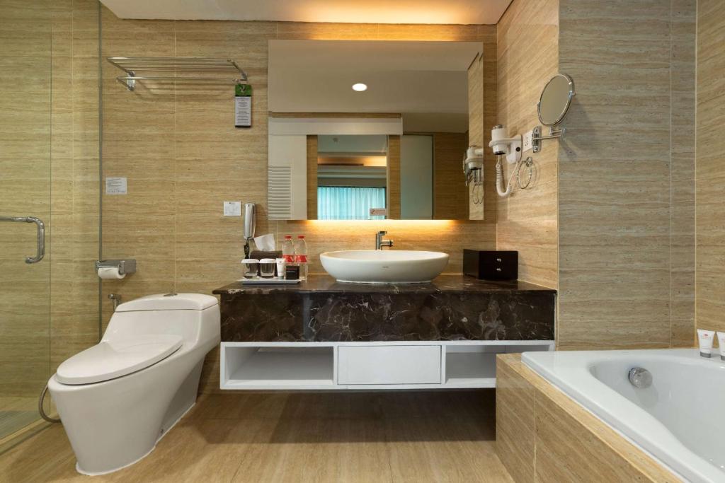 a bathroom with a sink and a toilet and a tub at Wyndham Panbil Batam in Batam Center