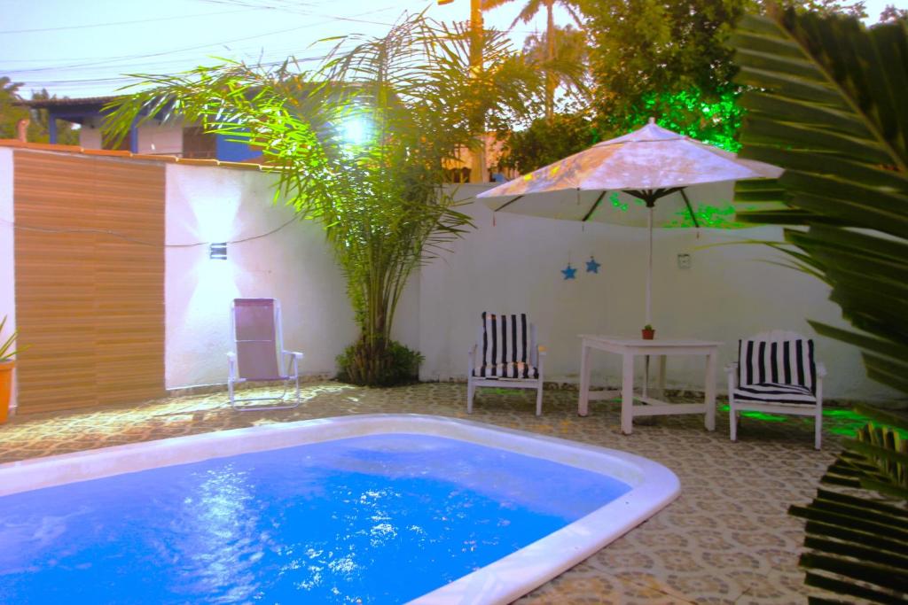 a swimming pool with two chairs and an umbrella at Pousada Canto de Paz in Arraial d'Ajuda