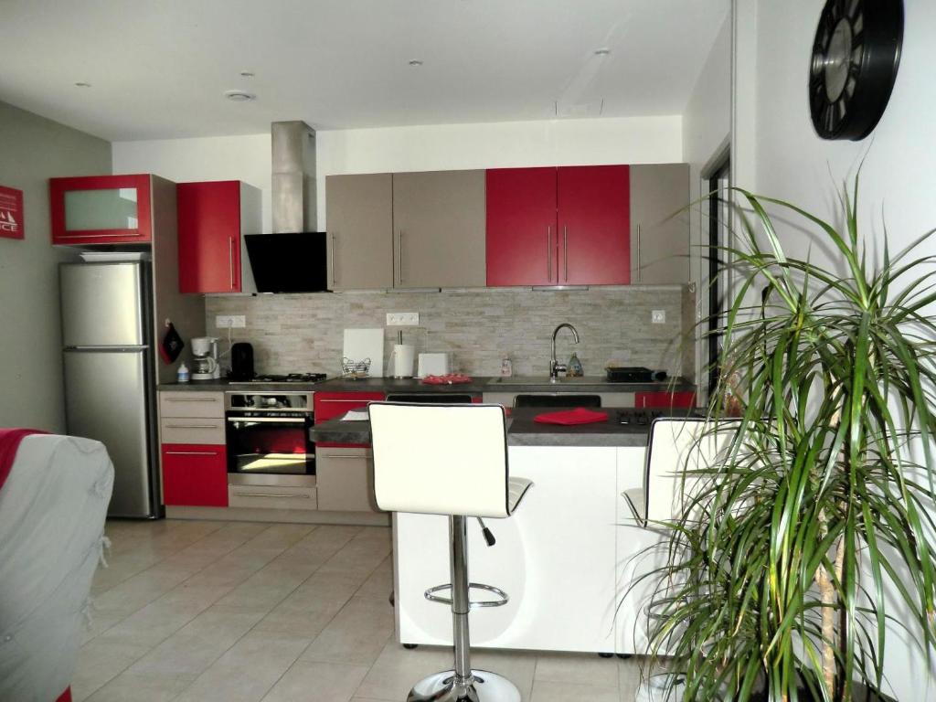 une cuisine avec des armoires rouges et des appareils blancs dans l'établissement Le magnolia, à Colomars