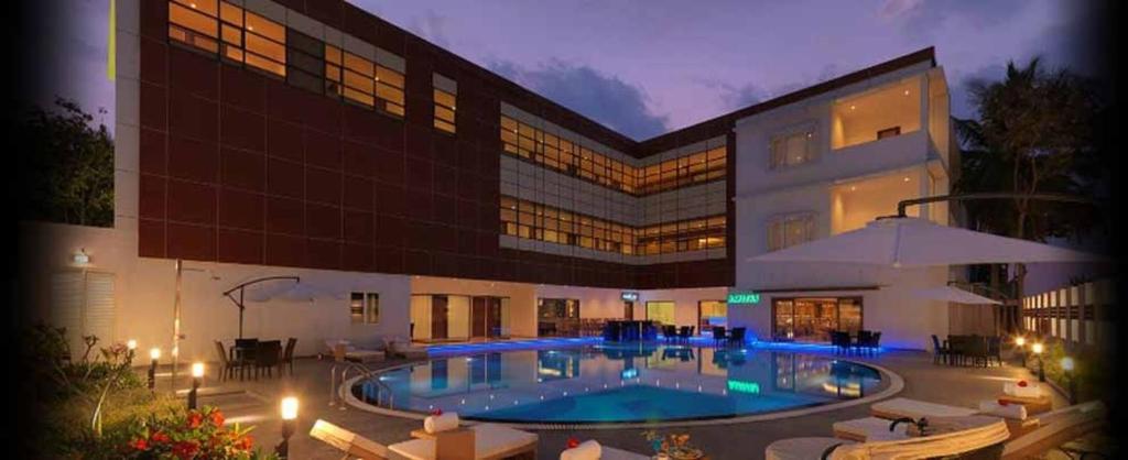 a hotel with a swimming pool in front of a building at Goldfinch Retreat Bangalore in Devanahalli-Bangalore