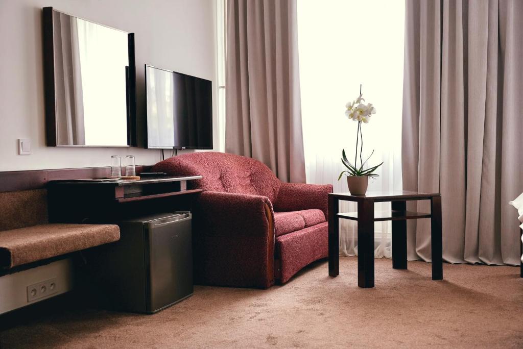 a living room with a chair and a table at Hotel Merkur - Jablonec nad Nisou in Jablonec nad Nisou