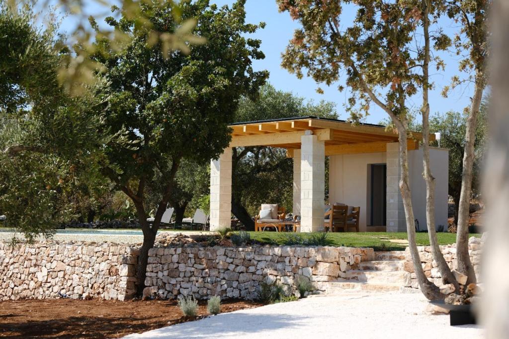 un pavillon avec un mur en pierre et des arbres dans l'établissement Borgo dei trulli Fanelli, à Castellana Grotte