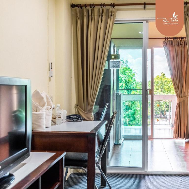 a living room with a table and a tv and a sliding glass door at rimtara residence patan in Chiang Mai