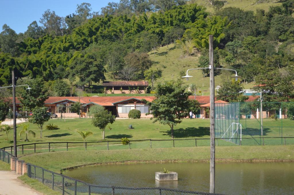 a house on a hill with a pond in front at Bougainville Hotel Fazenda in Amparo