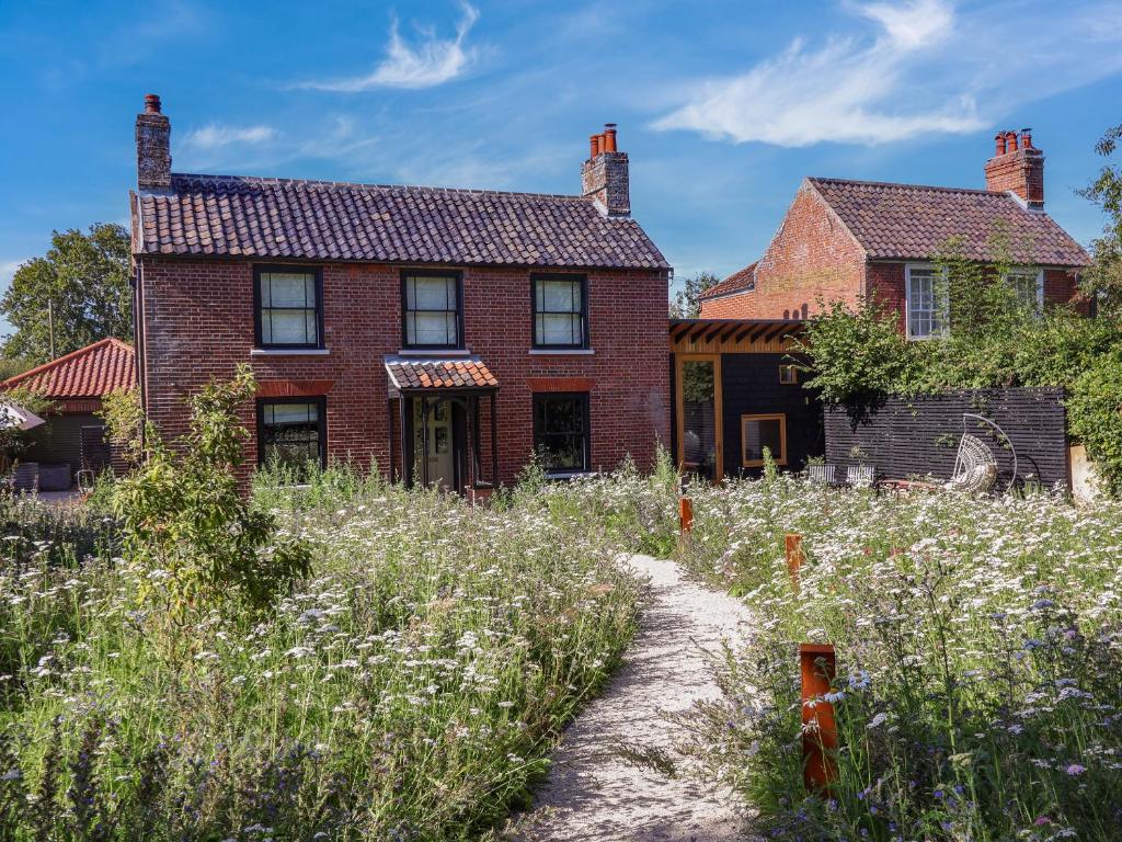 una vecchia casa di mattoni rossi con un campo di fiori di Oak Cottage a Lowestoft
