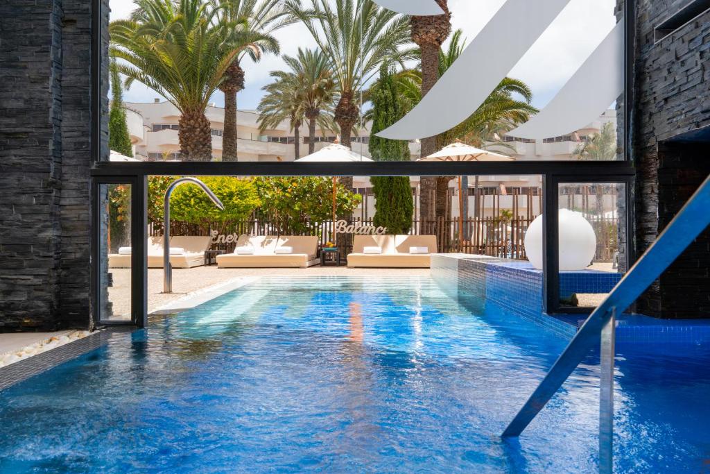 a swimming pool with palm trees in a building at Barceló Corralejo Bay - Adults Only in Corralejo