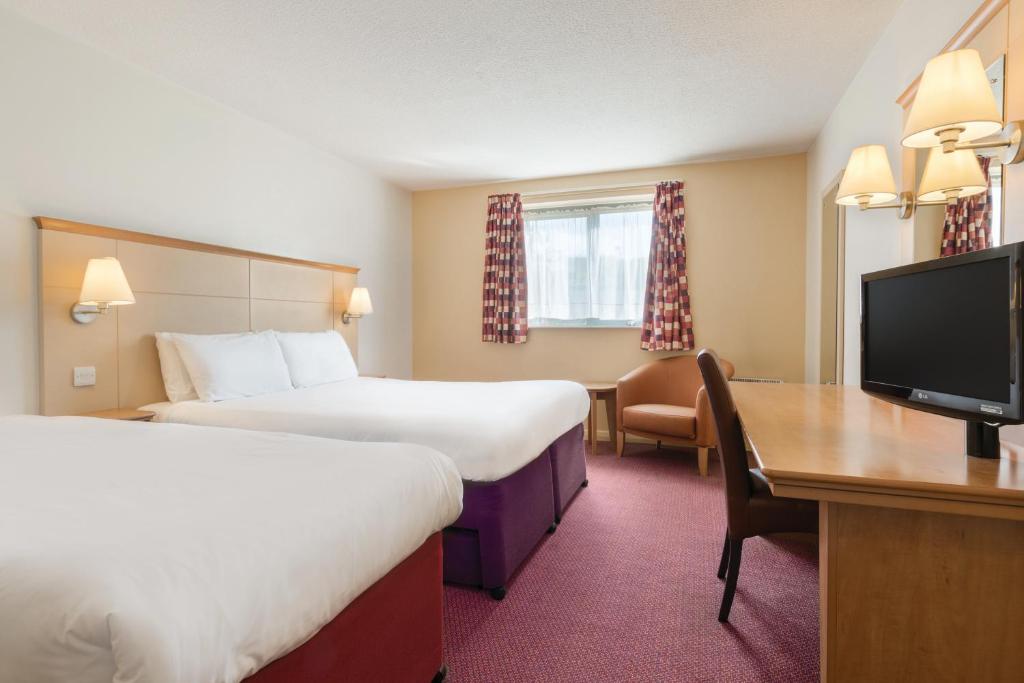 a hotel room with two beds and a desk and a tv at Days Inn Winchester in Winchester