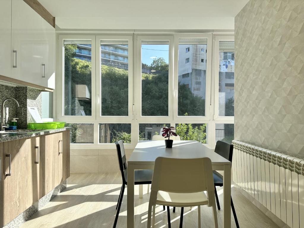 cocina con mesa blanca, sillas y ventanas en Front Beach I, en Sada