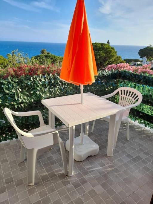 a table with an orange umbrella and two chairs at Il Faro in Scalea