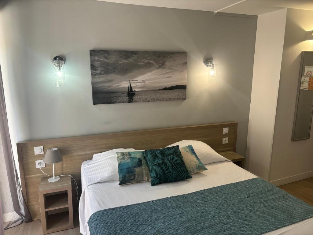 a bedroom with a bed and a painting on the wall at Hotel La Voile in Bormes-les-Mimosas
