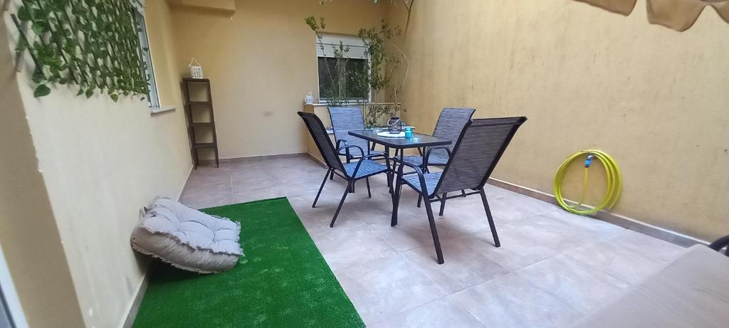 a patio with a table and chairs and a green rug at La casa bella di Chalkida in Chalkida